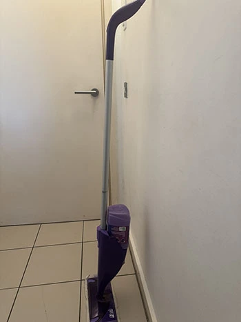 Side view of a Flash mop with a grey pole, purple handle, mop head, and cleaning solution